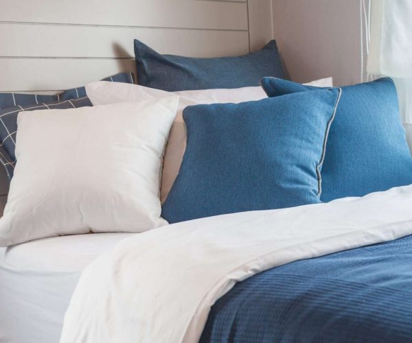 Many blue and white bedroom with warm light from window.